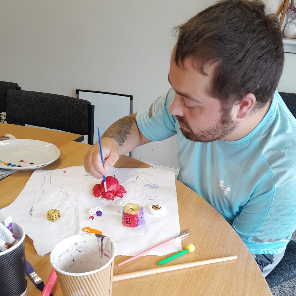 a man paints some of his clay creations