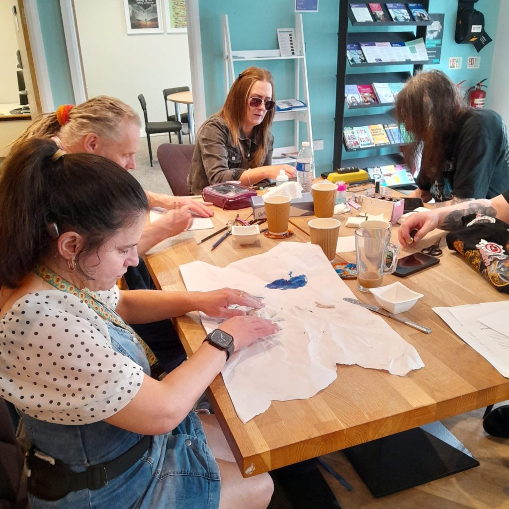 a group of adults sit around a table crafting various things